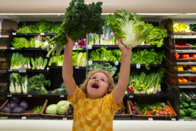 Bambino con lattuga bietole verdure bambino al supermercato vegetale ragazzino scegliendo il cibo in negozio