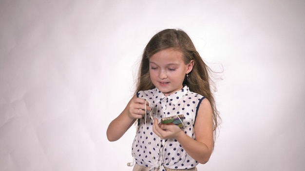 Bambino con le cuffie che ballano sullo sfondo dello studio La ragazza ascolta la musica sullo smartphone Bella bambina felice e carina ascolta la musica