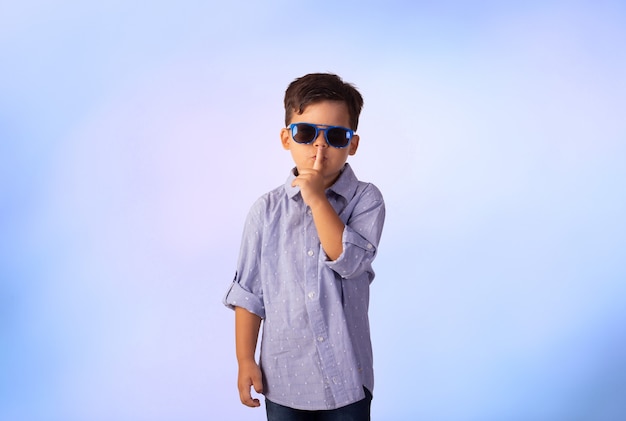 Bambino con le espressioni facciali in una foto in studio su sfondo colorato.