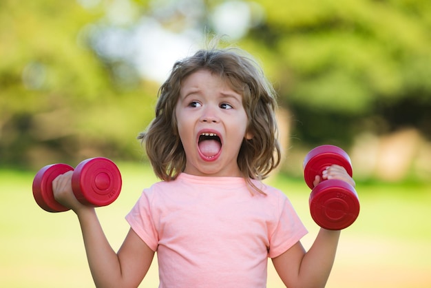 Bambino con manubri nel parco. Sport per bambini. Ragazzo attivo, concetto di stile di vita sano.