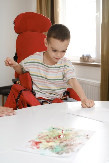 Bambino con paralisi cerebrale che dipinge disturbi fisici mentali terapia artistica