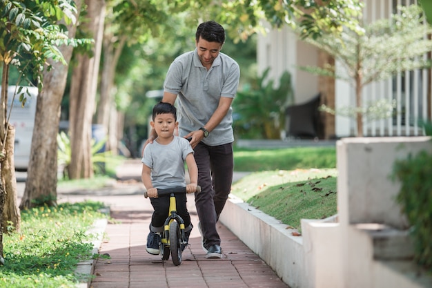 Bambino con suo padre che impara come andare in bicicletta