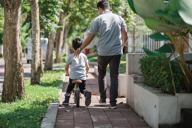 Bambino con suo padre che impara come andare in bicicletta