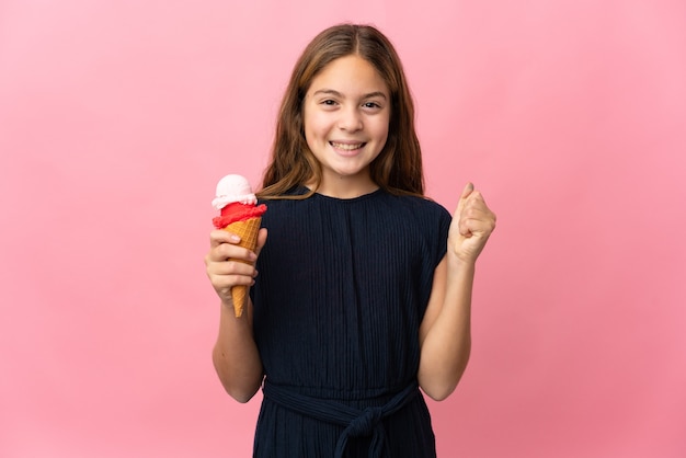 Bambino con un gelato alla cornetta sopra la parete rosa isolata che celebra una vittoria nella posizione del vincitore