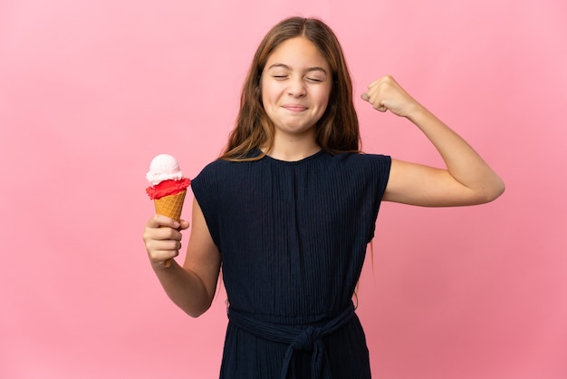 Bambino con un gelato alla cornetta sopra la parete rosa isolata che fa il gesto forte