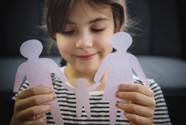 Bambino con una famiglia di carta nelle sue mani.