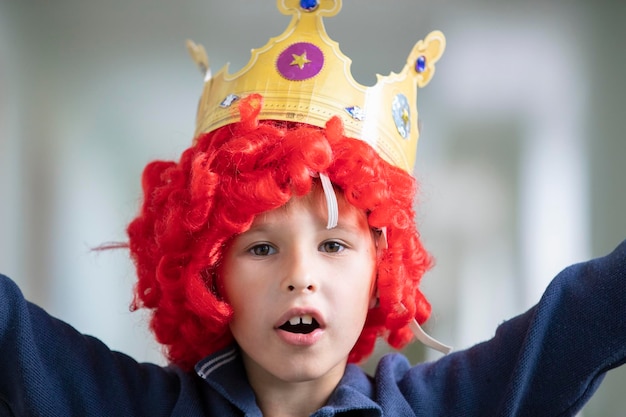 Bambino con una parrucca rossa e una corona Ragazzo del pagliaccio