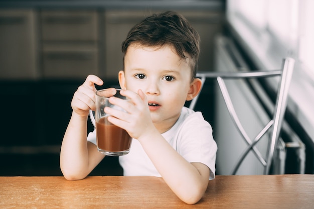 bambino con una tazza di cioccolata calda o cacao, sembra e sorride molto carino