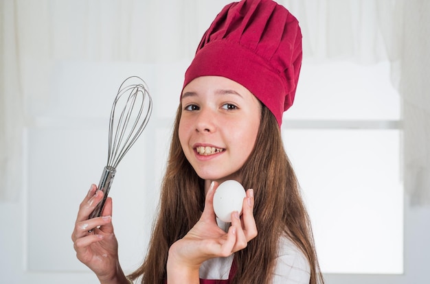 Bambino con utensile da cucina uovo e frullino