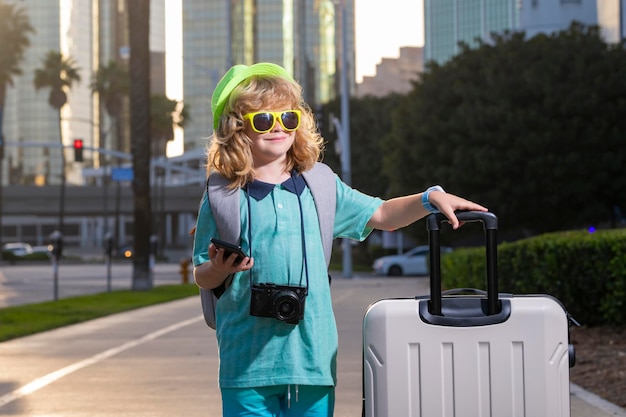 Bambino con valigia da viaggio in vacanza Concetto di viaggio e avventura per bambini Ragazzo bambino che va in vacanza con borsa da viaggio per bagagli all'aperto