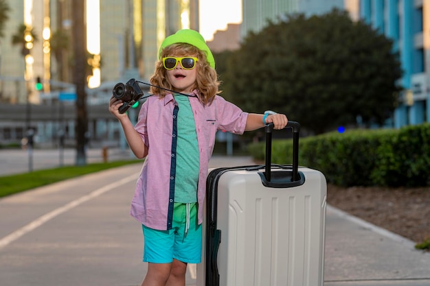 Bambino con valigia da viaggio in vacanza Concetto di viaggio e avventura per bambini Ragazzo bambino che va in vacanza con borsa da viaggio per bagagli all'aperto