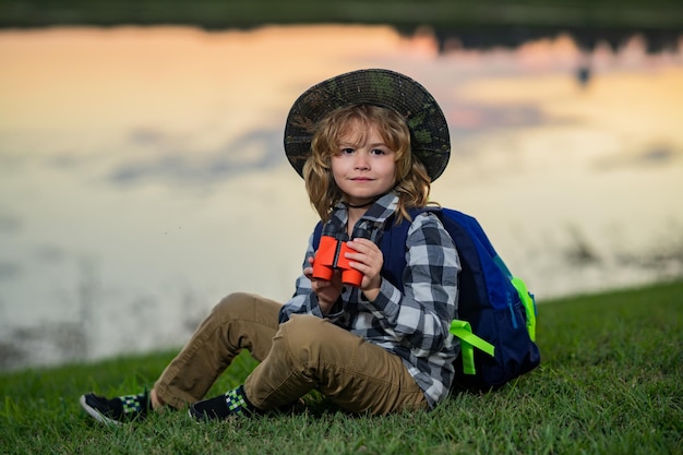 Bambino con zaino e binocolo Immaginazione o esplorazione nel parco Bambino felice che gioca con il binocolo Giovane esploratore turistico Vacanze e viaggi per bambini Viaggio estivo per bambini