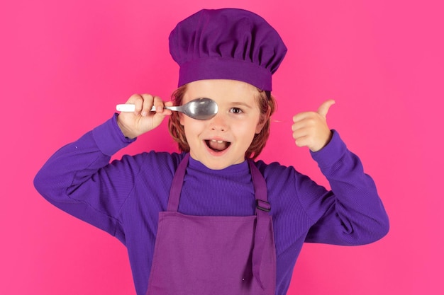 Bambino cuoco tenere cucchiaio Cuoco chef eccitato Bambino che indossa l'uniforme del fornello e cappello da chef che prepara il ritratto in studio del cibo