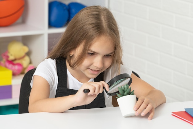 Bambino curioso che guarda la pianta attraverso la lente d'ingrandimento, curiosità