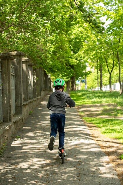 Bambino da solo nel parco su uno scooter in un casco