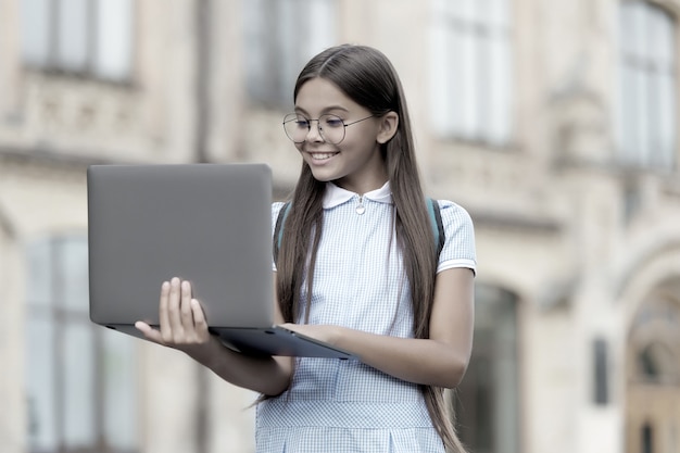 Bambino dall'aspetto intelligente nei gas che digita sul computer alla ricerca di informazioni in Internet per l'istruzione scolastica online, lo sviluppo dell'infanzia.