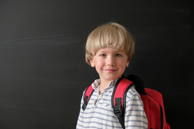 Bambino dalla scuola elementare con la borsa alla lavagna.