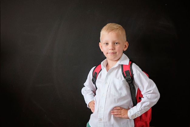 Bambino dalla scuola elementare con la borsa alla lavagna.