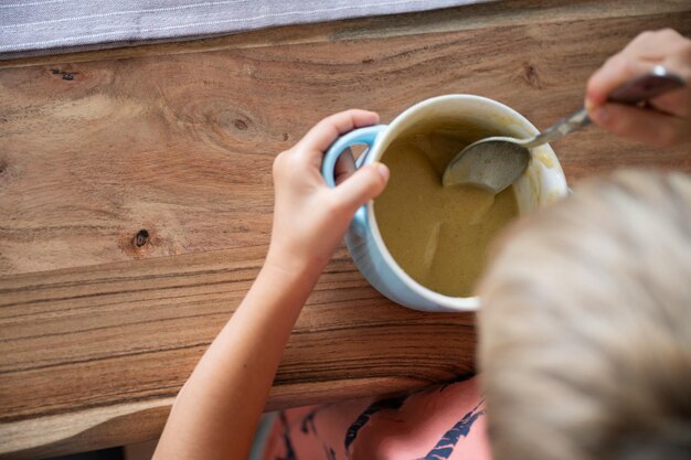 Bambino del bambino che mangia zuppa di crema sul tavolo da pranzo in legno