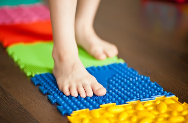 Bambino del ragazzino che cammina su una stuoia ortopedica di massaggio. Trattamento e prevenzione dei piedi piatti nei bambini.