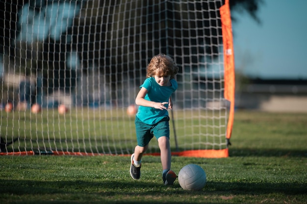 Bambino del ragazzo che dà dei calci al calcio sul campo sportivo durante la partita di calcio Ragazzo che dà dei calci al calcio sul campo