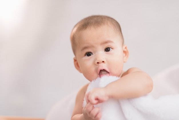 Bambino dell&#39;Asia del ritratto sul letto bianco