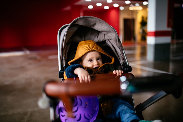 Bambino di 1 anno nel passeggino per bambini in un garage