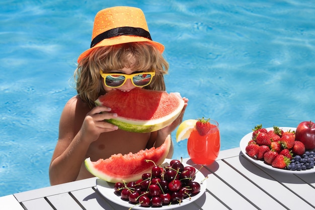 Bambino di frutta estiva mangia anguria bambino con frutta estica in piscina bambino in piscina che gioca e