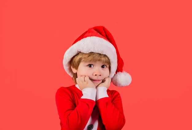 Bambino di natale in cappello rosso festa di capodanno ragazzo sorpreso in costume da babbo natale ragazzino a babbo natale