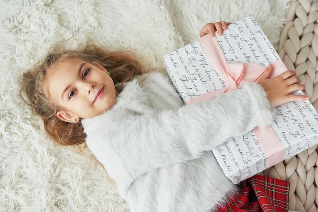 Bambino di Natale sullo sfondo dell'albero di Natale con regalo.