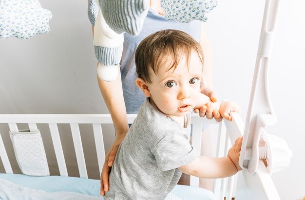 Bambino di nove mesi che gioca nella culla con sua madre. il suo concetto bambino e madre. maternità