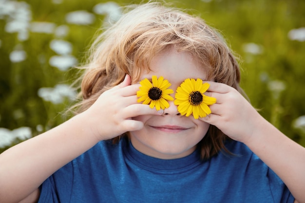 Bambino di primavera divertente ragazzino con la margherita negli occhi