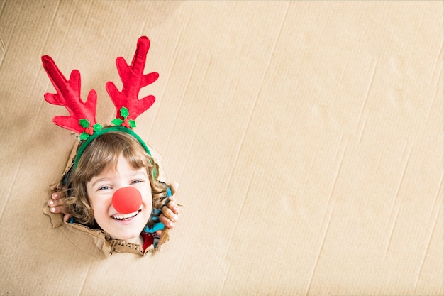 Bambino divertente che guarda attraverso il foro su cartone Bambino che gioca a casa Vacanze di Natale