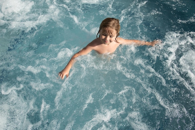 Bambino divertente che si gode l'estate nella vasca idromassaggio della piscina