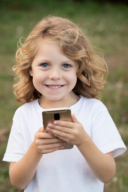 Bambino divertente con i capelli lunghi in possesso di un cellulare