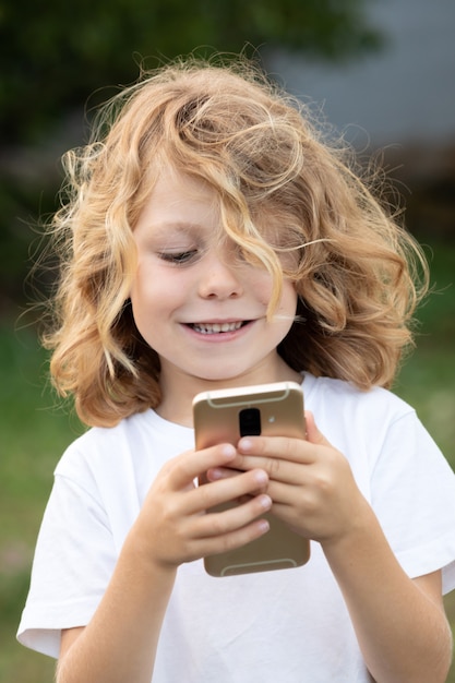 Bambino divertente con i capelli lunghi in possesso di un cellulare