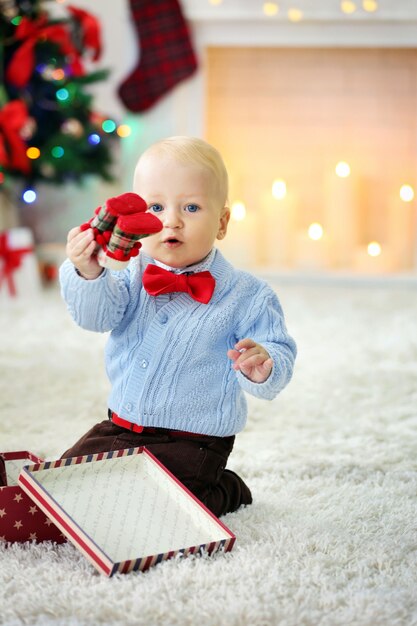 Bambino divertente con scatola regalo e albero di Natale e camino sullo sfondo