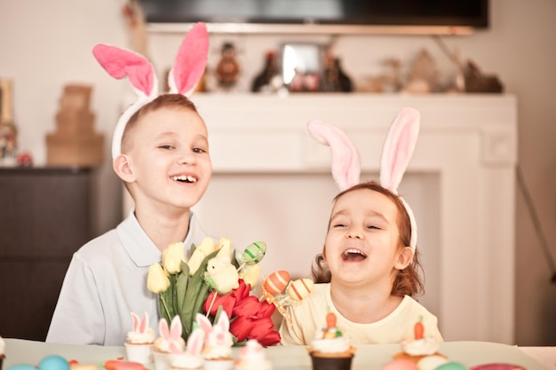 Bambino divertente della ragazza e del ragazzo che indossa le orecchie del coniglietto in primavera a casa