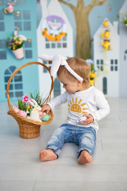 Bambino divertente e felice con le orecchie di coniglio che gioca alla caccia agli uova di Pasqua