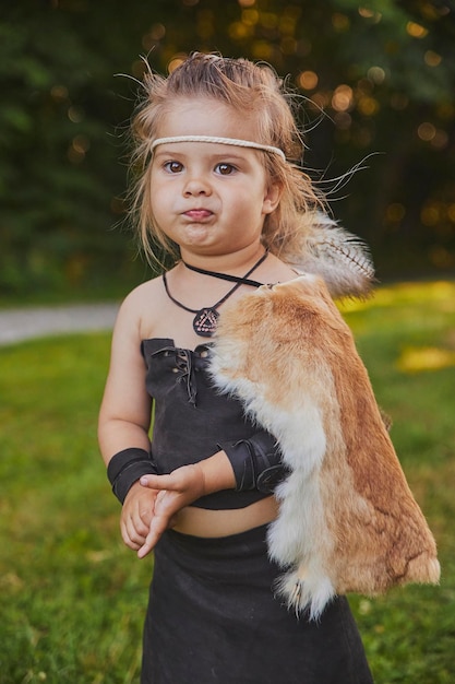 Bambino divertente vestito con i vestiti delle persone primitive