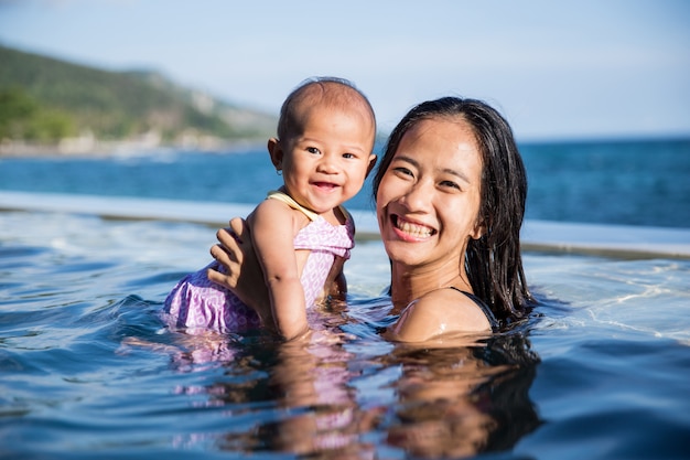 Bambino divertirsi in piscina con la madre