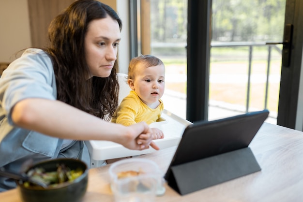 Bambino e genitori impegnati in un gadget digitale durante un pranzo a casa