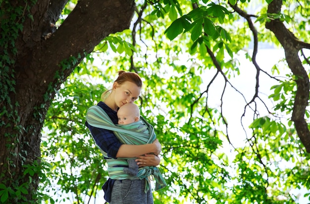 Bambino e mamma sulla natura verde Mamma con bambino in fascia Portabebè in cotone avvolgente