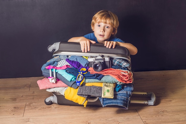 Bambino e valigia da viaggio. Bambini e bagagli imballati per le vacanze pieni di vestiti, bambini e viaggi in famiglia