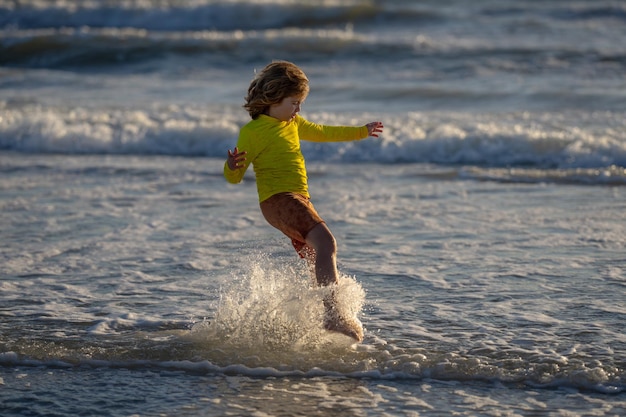 Bambino eccitato che gioca nel mare bambino che si diverte all'aperto bambino che sguazza nel mare bambino gioca con il mare wa