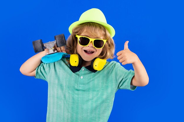 Bambino eccitato con il pollice in su Bambino con lo skateboard in studio Bambino che si diverte con il penny board Penny