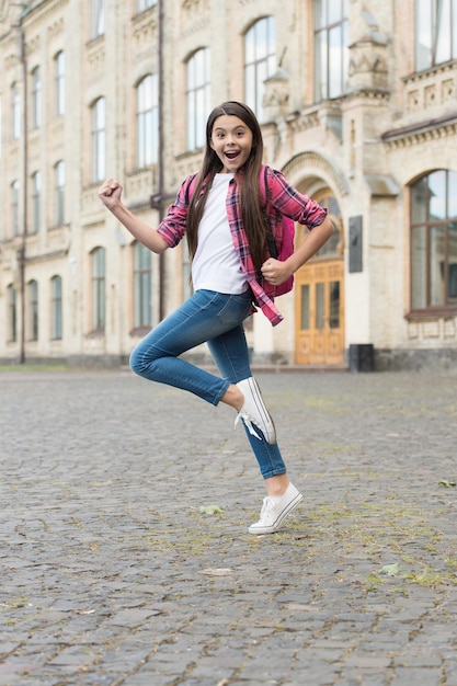 Bambino energico felice con la borsa di scuola correre in stile casual moda all'aperto infanzia