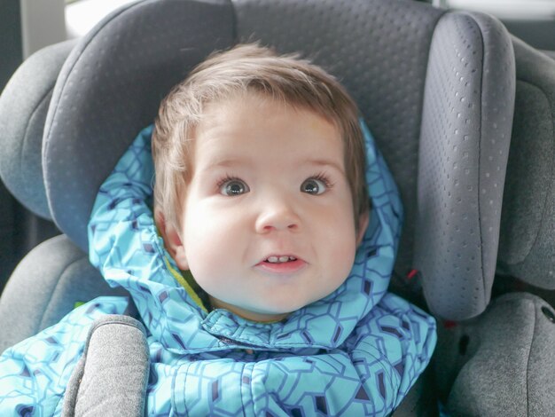 Bambino facente smorfie in un seggiolino per auto. Sicurezza dei bambini nel seggiolino durante il sonno.