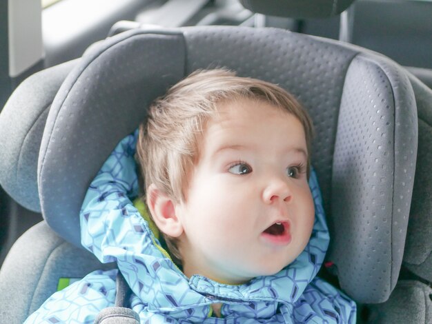 Bambino facente smorfie in un seggiolino per auto. Sicurezza dei bambini nel seggiolino durante il sonno.