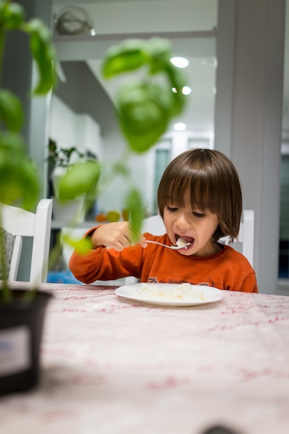 Bambino felice a casa a mangiare cibo